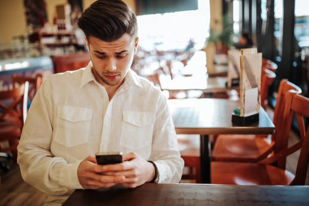 istock Young man using smartphone in urban cafe 1214077815