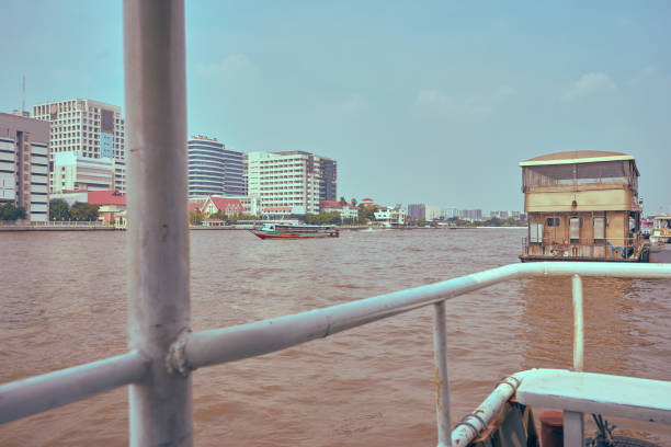 Photos of the city of Bangkok in Thailand taken from a boat on the river, you can see piers, houses, high-rise buildings, buildings, ships, boats