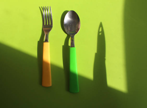 istock Fork, knife and spoon with shadows on bright green background 1214084033