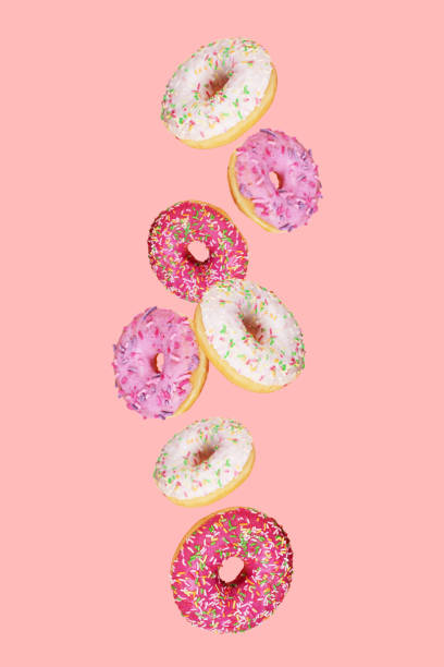 istock Falling doughnuts with colored glaze on trendy pink background.  Levitating food. 1214085913
