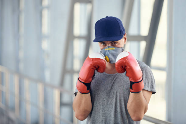 istock A guy in a protective mask and boxing gloves fights against viruses. Coronavirus covid-19 concept photo. 1214088618