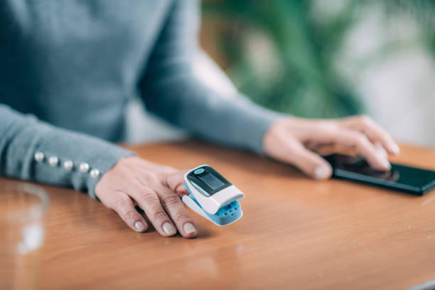 Senior Woman Using Pulse Oximeter and Smart Phone, Measuring Oxygen Saturation Senior Woman Using Pulse Oximeter and Smart Phone, Measuring Oxygen Saturation pulse oxymeter stock pictures, royalty-free photos & images