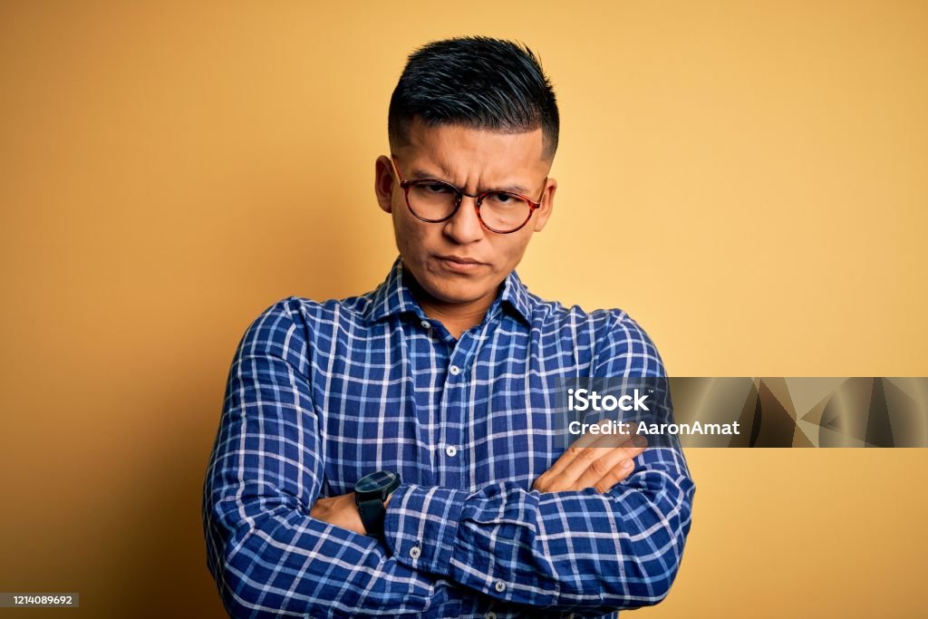 노란색 배경 에 캐주얼 셔츠와 안경을 입고 젊은 잘 생긴 라틴 남자는 회의적이고 긴장 교차 팔로 얼굴에 표정을 거부 부정적인 사람 남자에  대한 스톡 사진 및 기타 이미지 - Istock