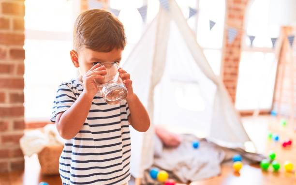 Beautiful toddler boy drinking glass of water at kindergarten Beautiful toddler boy drinking glass of water at kindergarten only boys stock pictures, royalty-free photos & images