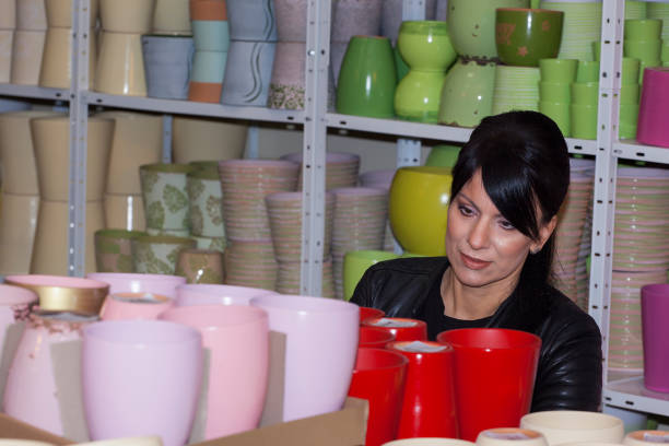 beautiful girl in a black leather jacket, looks at ornaments and pots, in a flower shop