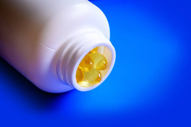 istock Fish oil placed near a plastic bottle on a blue background 1214093977