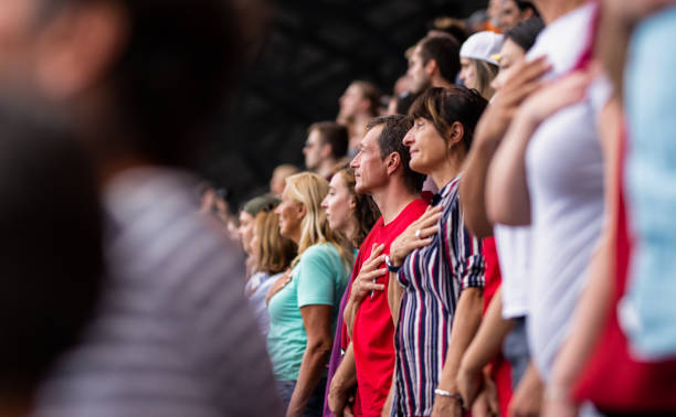 People During National Anthem On A Sports Event Standing crowd on a stadium during national anthem with their hands on heart. national anthem stock pictures, royalty-free photos & images