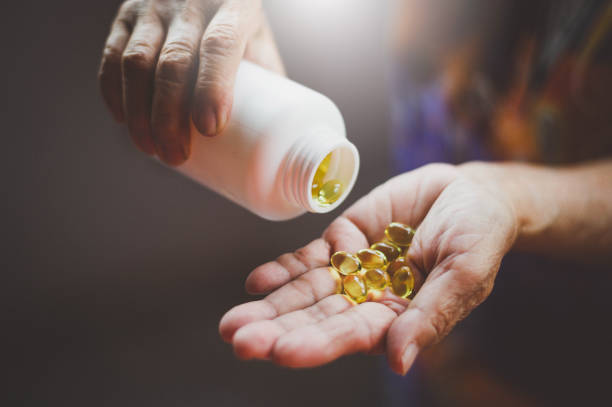손에 붓는 오메가 3 피시 오일 캡슐 1병 - vitamin d capsule fish oil yellow 뉴스 사진 이미지
