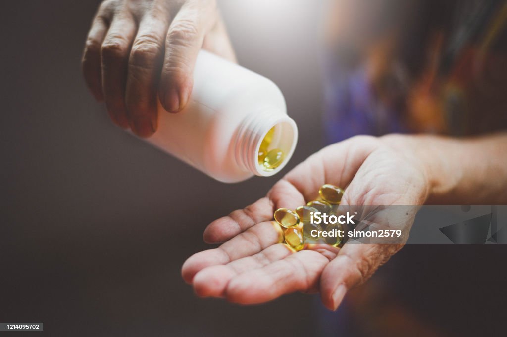 Bottle of omega 3 fish oil capsules pouring into hand Image of Bottle of omega 3 fish oil capsules pouring into hand. Vitamin D Stock Photo