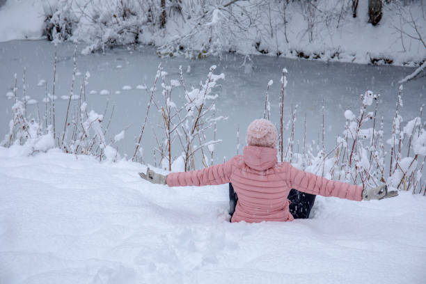 istock Female hiker relaxes by snowy river bank 1214096113