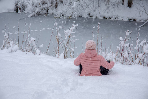 istock Female hiker relaxes by snowy river bank 1214096696