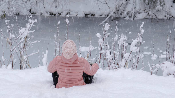 istock Female hiker relaxes by snowy river bank 1214096748