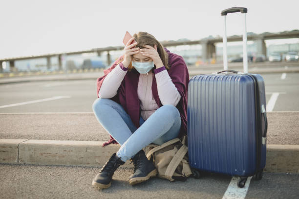 istock Young woman wearing medical mask, with a suitcase 1214096821