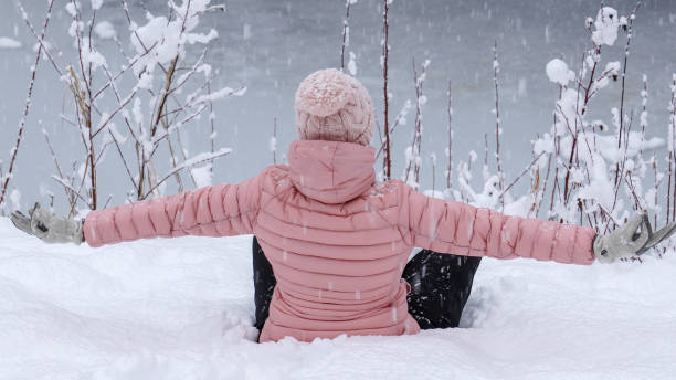 Female hiker relaxes by snowy river bank