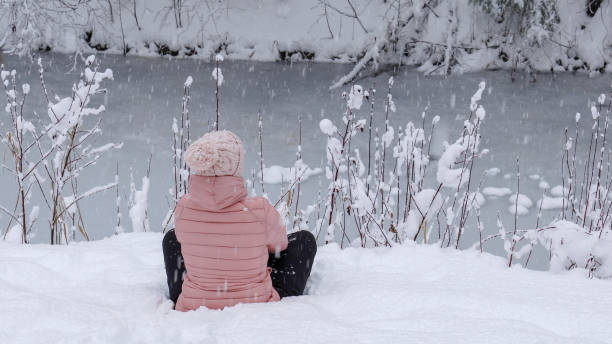 istock Female hiker relaxes by snowy river bank 1214096859
