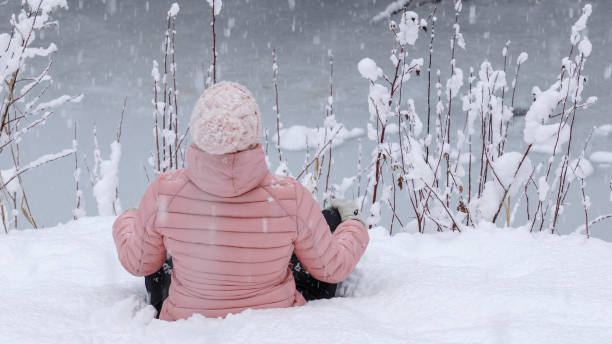 istock Female hiker relaxes by snowy river bank 1214097043