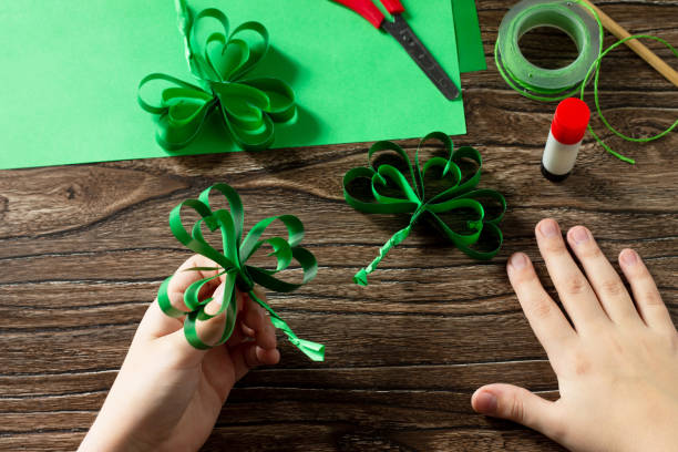 istock Child holds St. Patrick's Day clover, craft from paper. Handmade. Children's art project, needlework, crafts for children. 1214097219