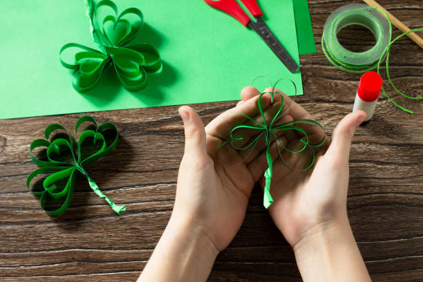 istock Child holds St. Patrick's Day clover, craft from paper. Handmade. Children's art project, needlework, crafts for children. 1214097240