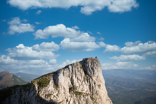 Shot of a young man having coffee while looking down at the view from a mountain top