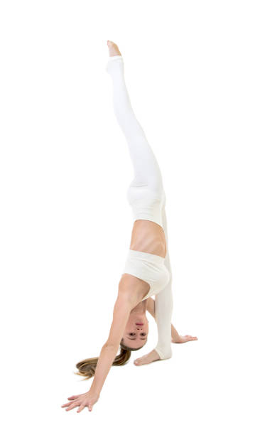 istock A young woman in a white suit performs acrobatic elements and yoga. 1214098589