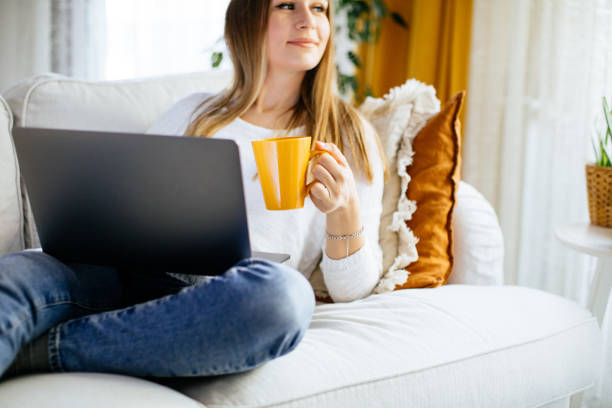 istock Happy smiling woman sitting on sofa and using laptop 1214098885