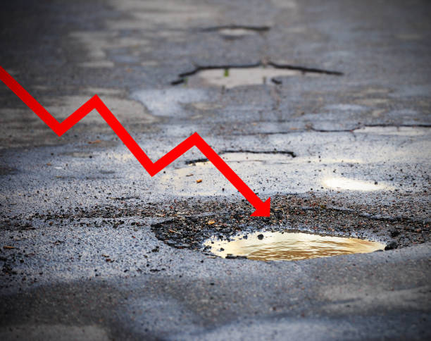 istock Financial graph going down into pot hole on asphalt road 1214100092