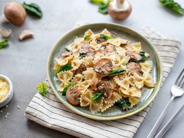 istock farfalle with mushrooms and spinach on a gray concrete background. 1214100151