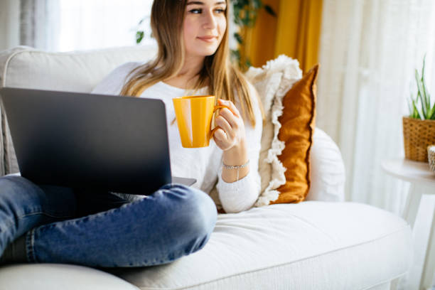 istock Happy smiling woman sitting on sofa and using laptop 1214102367