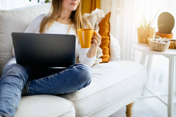 istock Happy smiling woman sitting on sofa and using laptop 1214102716