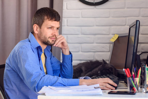 istock Freelancer thoughtfully looks out the window, sitting at his workplace 1214105176