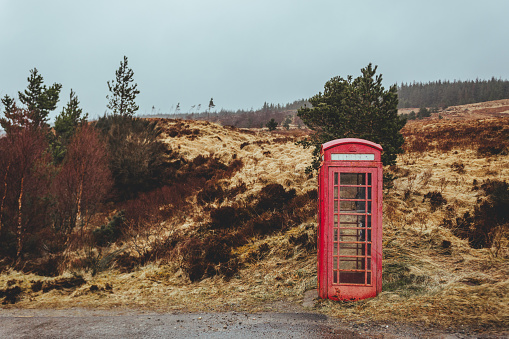 Traditional red telephone box on a side of a road in the Scottish Highlands; \