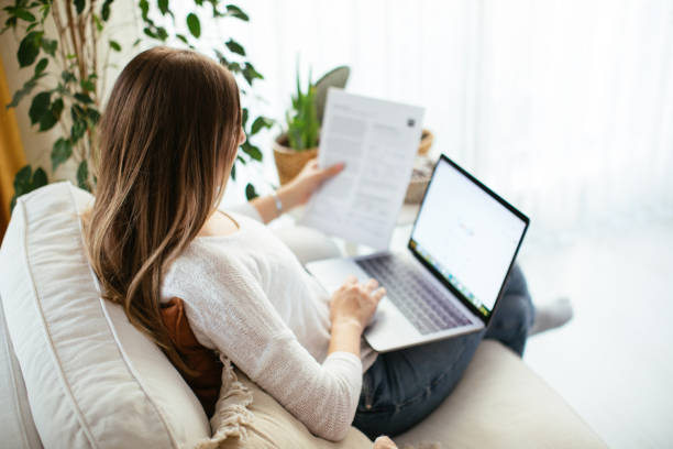 istock Happy smiling woman sitting on sofa and using laptop 1214106622