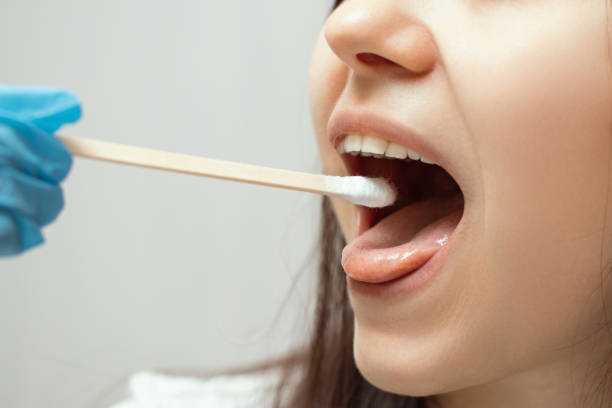 istock Taking a medical sample - a throat swab for a coronavirus test. A nurse's hand takes a sample from a young girl 1214107953