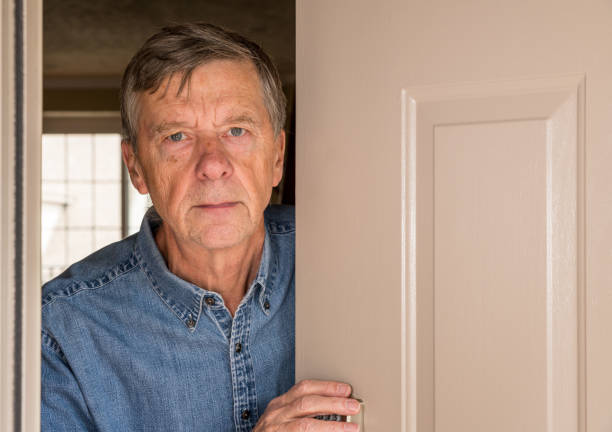 istock Senior man peering through front door for visitors during quarantine 1214108040