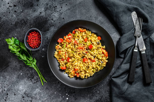 istock Bulgur with vegetables and meat on a plate. Black background. Top view 1214109307