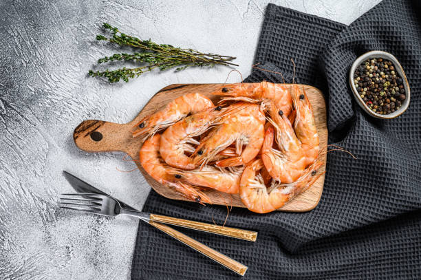 istock Cooked fresh giant prawns on a wooden chopping Board. White background. Top view 1214109558