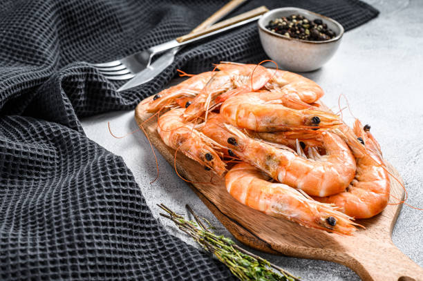istock Cooked fresh giant prawns on a wooden chopping Board. White background. Top view 1214109605