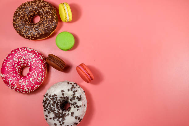 istock Tasty donuts and macaroons on pink background. Top view, copy space 1214110561