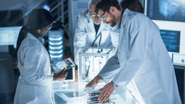 istock In Technology Research Laboratory: Diverse Team of Industrial Scientists, Engineers, Developers Work with Digital Whiteboard Showing Engine Blueprints, Efficiency Calculated by Neural Network 1214111339