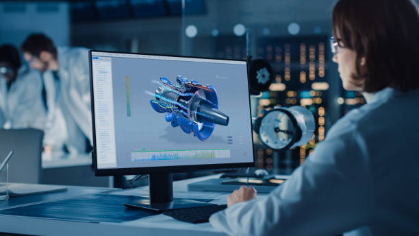 istock Over the Shoulder Shot: Female IT Scientist Uses Computer Showing CAD Software with Airplane Engine. In the Background Technology Development Laboratory with Scientists, Engineers Working 1214111484