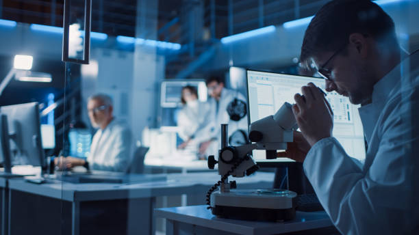 istock In Technology Research Laboratory: Diverse Team of Industrial Scientists, Engineers, Developers Gather Around Illuminated Table and Inspect Blueprints, Adjust 3D Printer, Choose Component Motherboard 1214112059