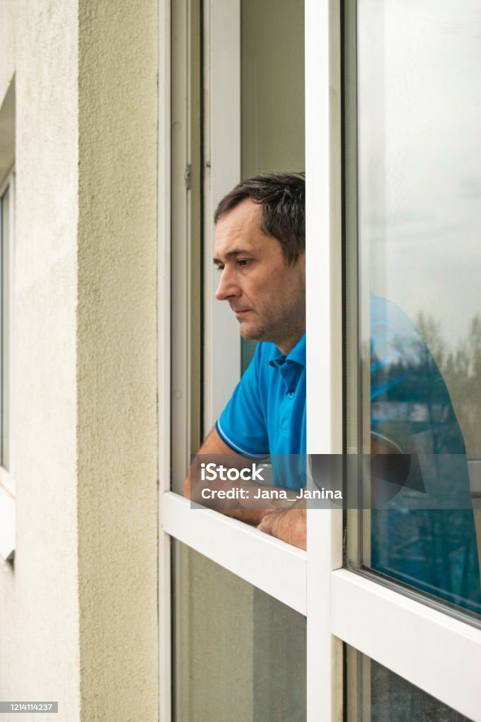 The Man Looks Outside Standing At The Open Window Of His Apartment Staying  At Home During The Epidemic And Quarantine Stock Photo - Download Image Now  - iStock