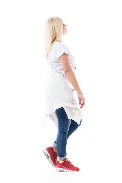 Side view of happy confident trendy mid age woman walking and smiling looking away. Full body isolated on white background.