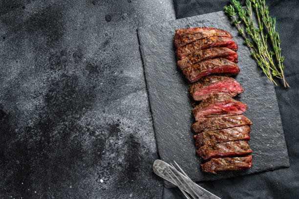 Grilled roasting rare sliced vegas strip steak. Marble meat beef. Black background. Top view. Copy space Grilled roasting rare sliced vegas strip steak. Marble meat beef. Black background. Top view. Copy space. blade roast stock pictures, royalty-free photos & images