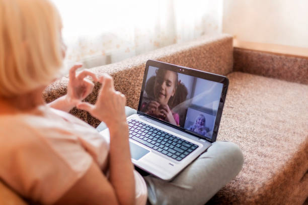 ragazza carina che parla con sua nonna all'interno della videochat su laptop, vita in tempo di quarantena - rear view family isolated child foto e immagini stock