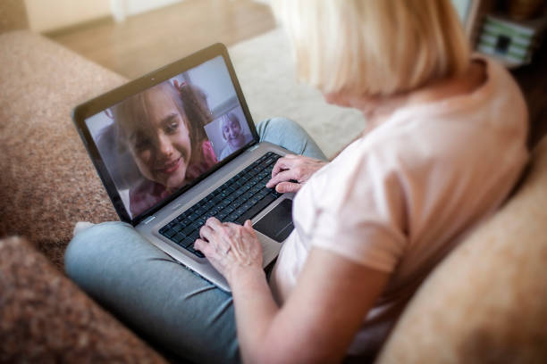 fille mignonne parlant avec sa grand-mère dans le chat vidéo sur l’ordinateur portatif, la vie dans le temps de quarantaine - grandmother child grandparent isolated photos et images de collection