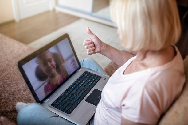 cute girl talking with her grandmother within video chat on laptop, life in quarantine time - senior adult technology child internet imagens e fotografias de stock