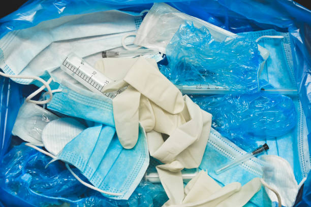 Medical trash. Coronavirus protection equipment in medical waste bin. Used face masks and sterile gloves. Doctor uniform for patient treatment in hospital. Prevention the spread of COVID-19. stock photo
