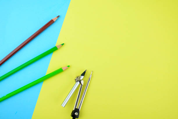 istock Some different colored pencil crayons and a silver pencil attached to a pencil compass scattered on a paper background 1214118310