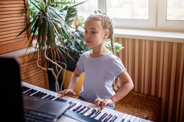 young musician playing classic digital piano at home during online class at home, self-isolation - practicing piano child playing imagens e fotografias de stock